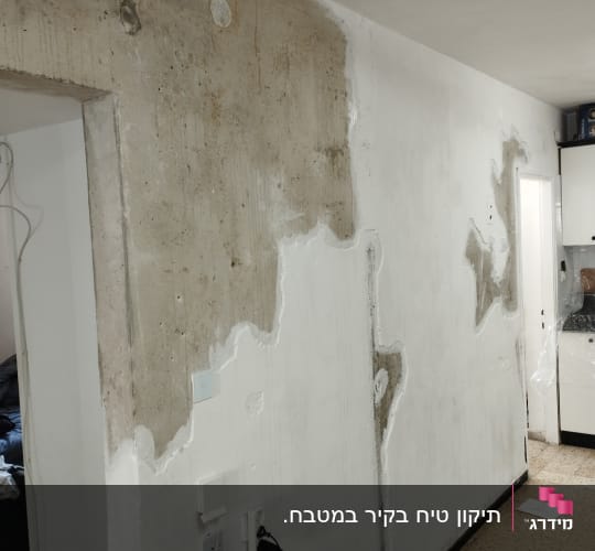 קיר עם טיח מתקלף וחומרי תיקון על הרצפה